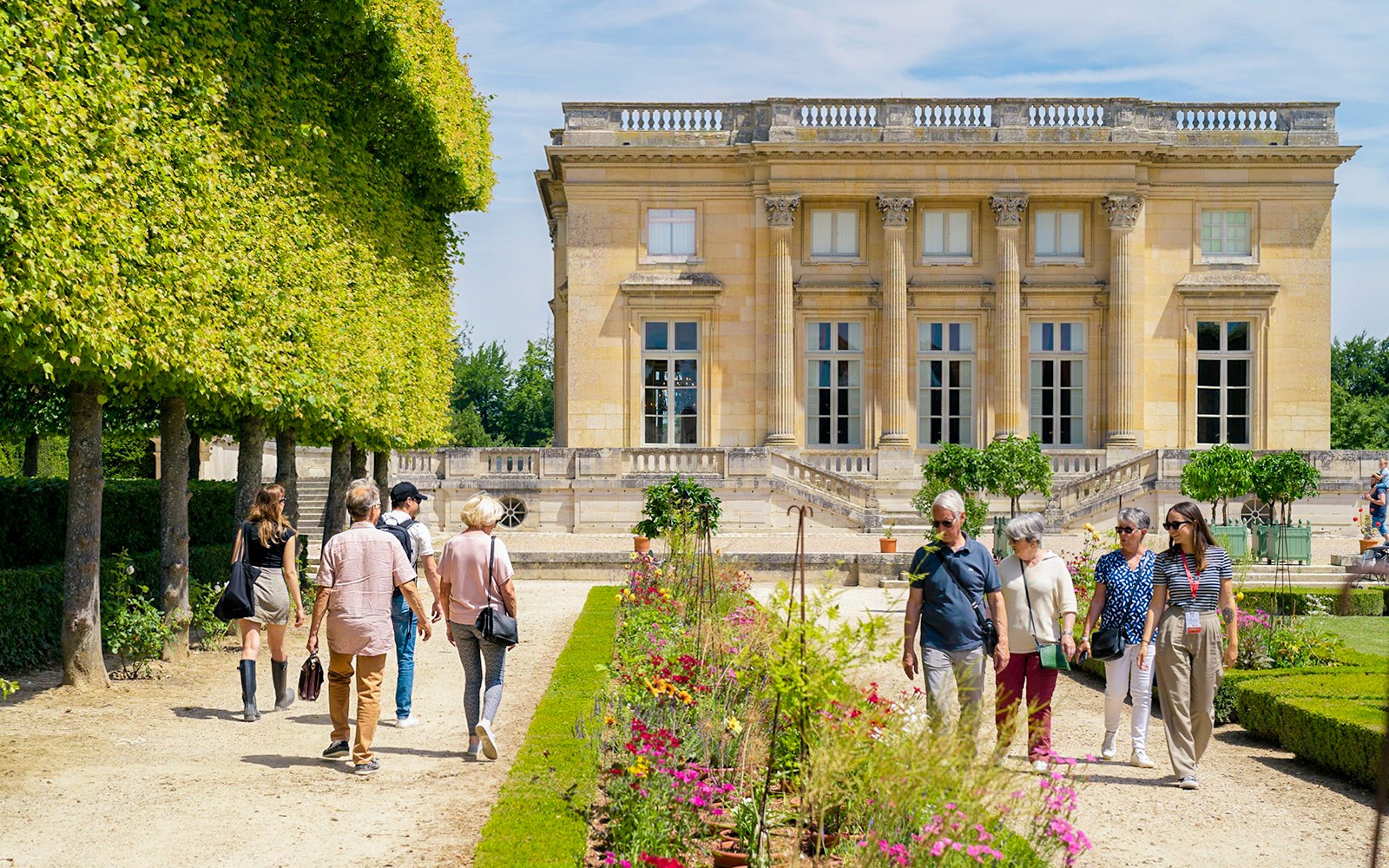 Tourists with guide exploring gardens at Petit Trianon, Versailles.