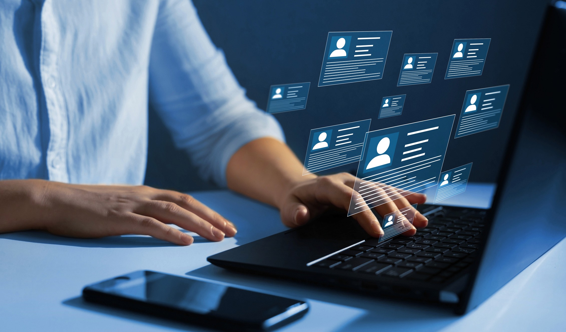 Woman looking up a persons resume on a laptop.