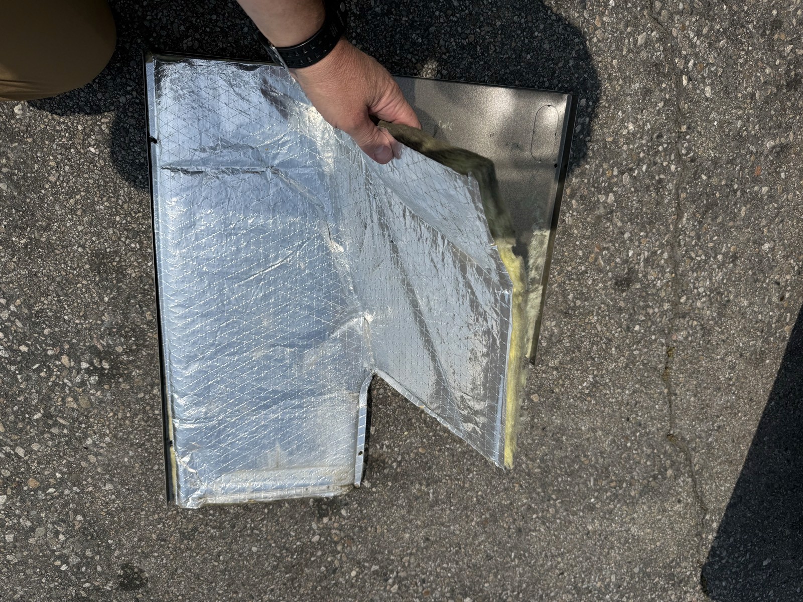 Foil-faced insulation peeled back from an air handler access panel during diagnosis.