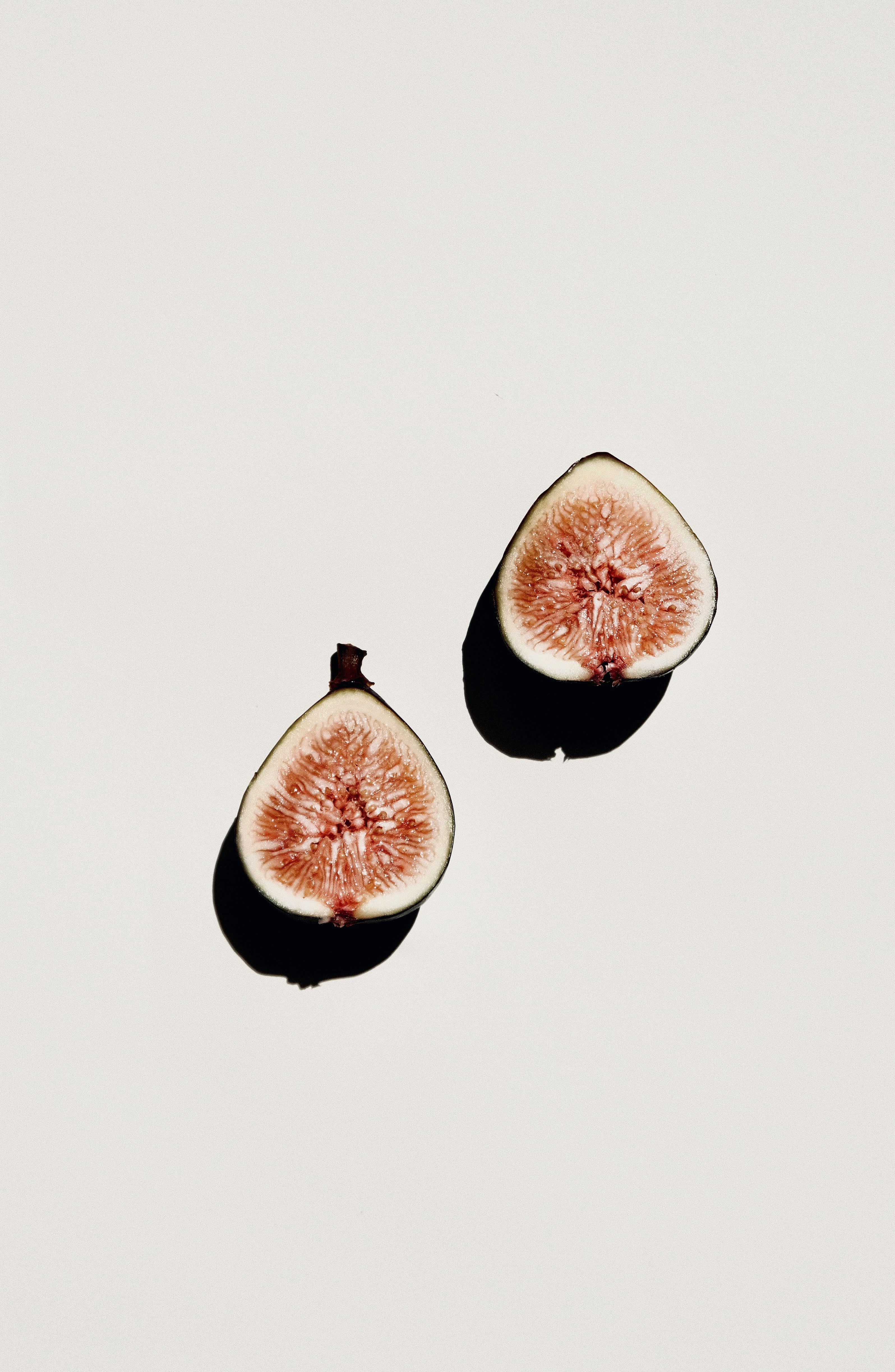 Two halves of a fig on a white background