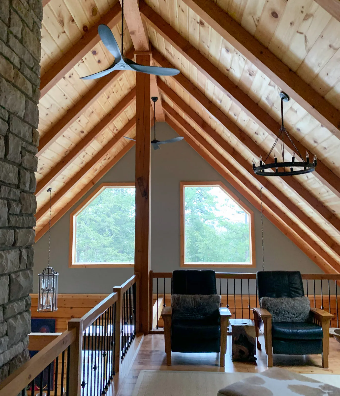 Loft space with two leather chairs under exposed wood beam A-frame roof.