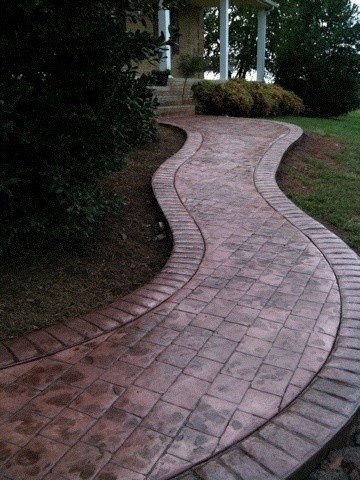 red stained, stamped, textured concrete patio, pathway with a beautiful curved pattern in front of the house