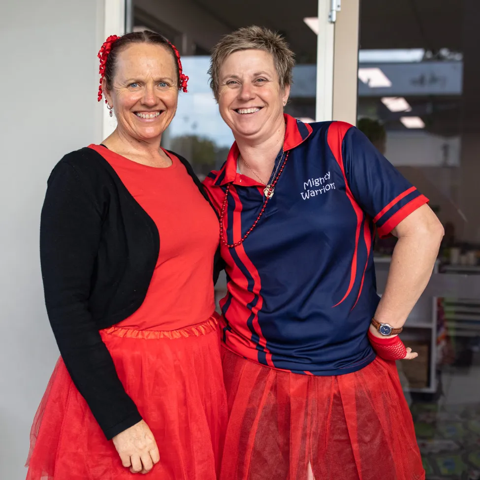 Childcare educator playing with two young girls in colourful dresses during outdoor activities at Kaleidoscope Kids Redbank.