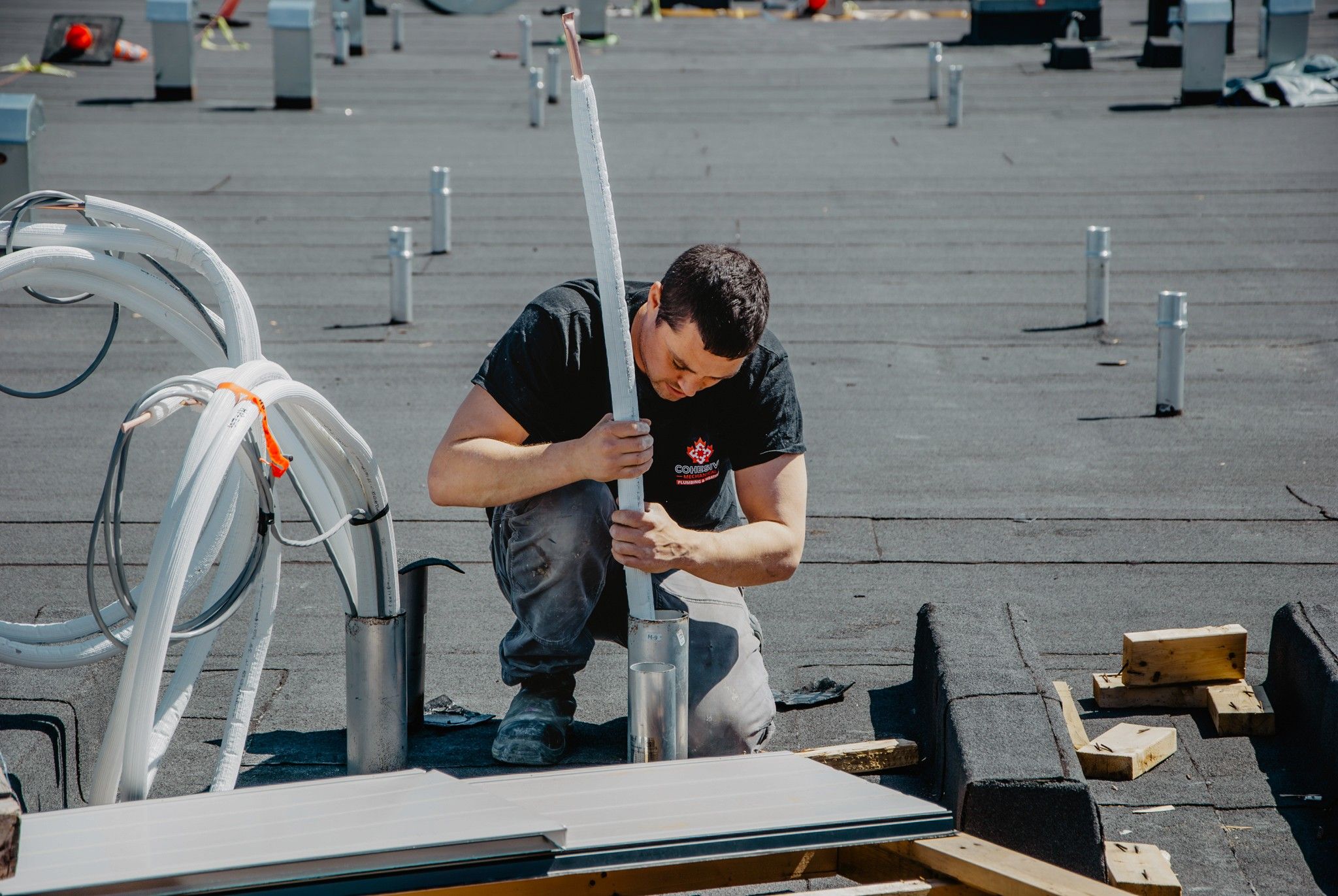 Chilliwack HVAC technician installing pipes on rooftop in Fraser Valley, British Columbia for plumbing services.