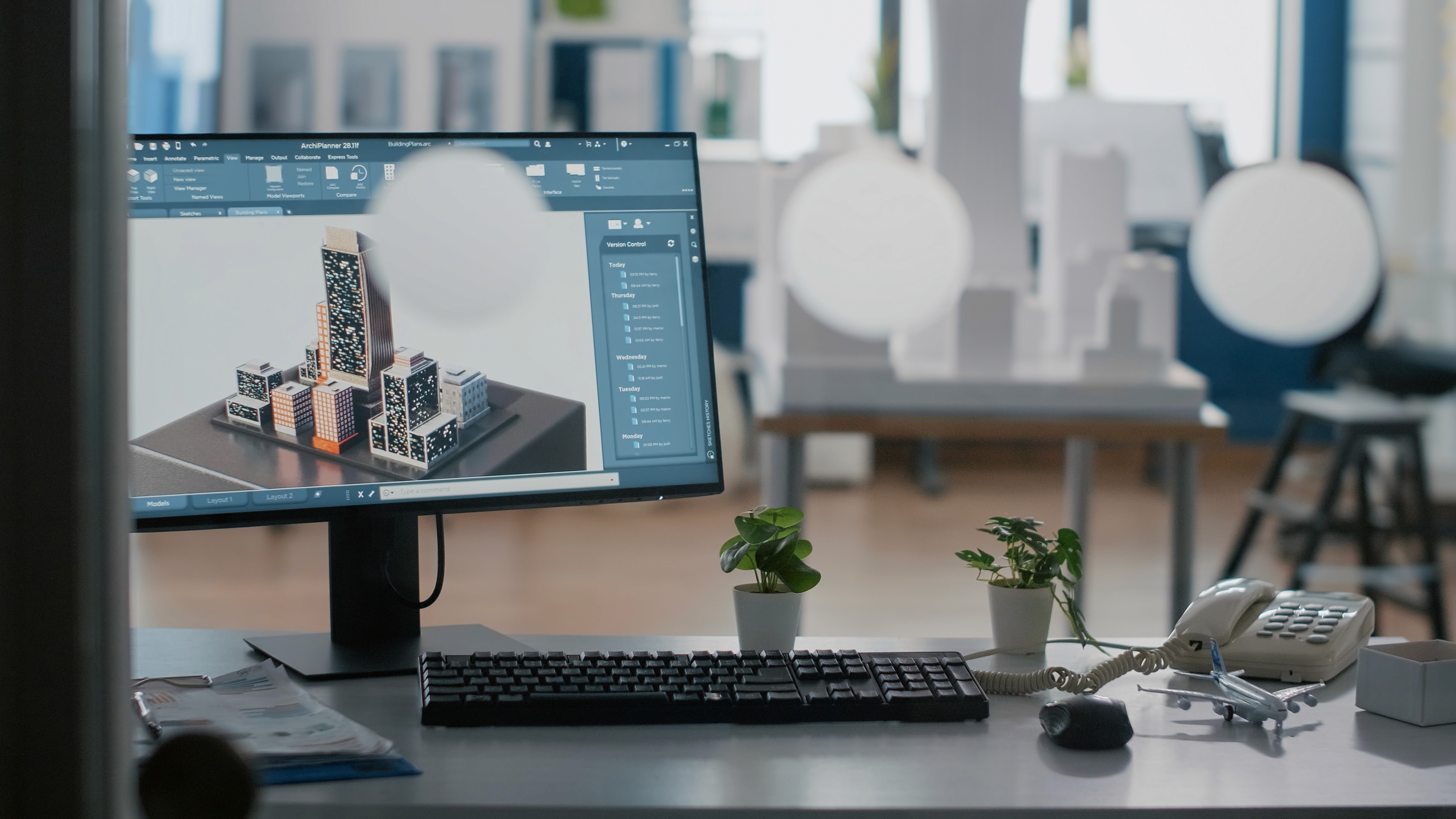 3D architectural model of modern city buildings displayed on desktop monitor in design studio