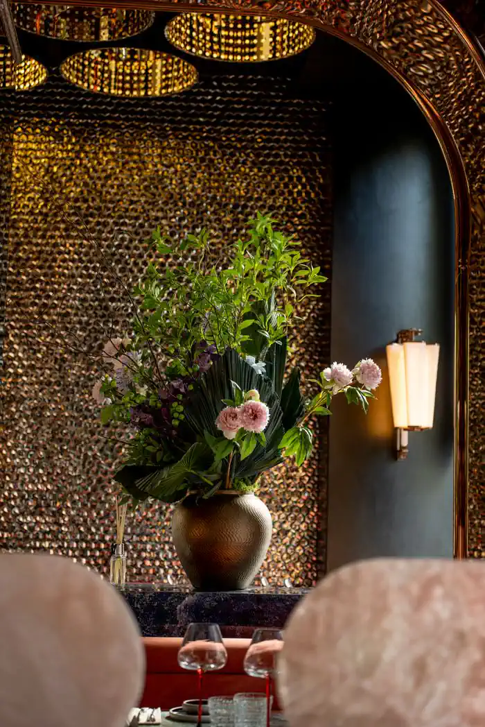 Bouquet of peonies in front of a copper wall and a gilded wall light