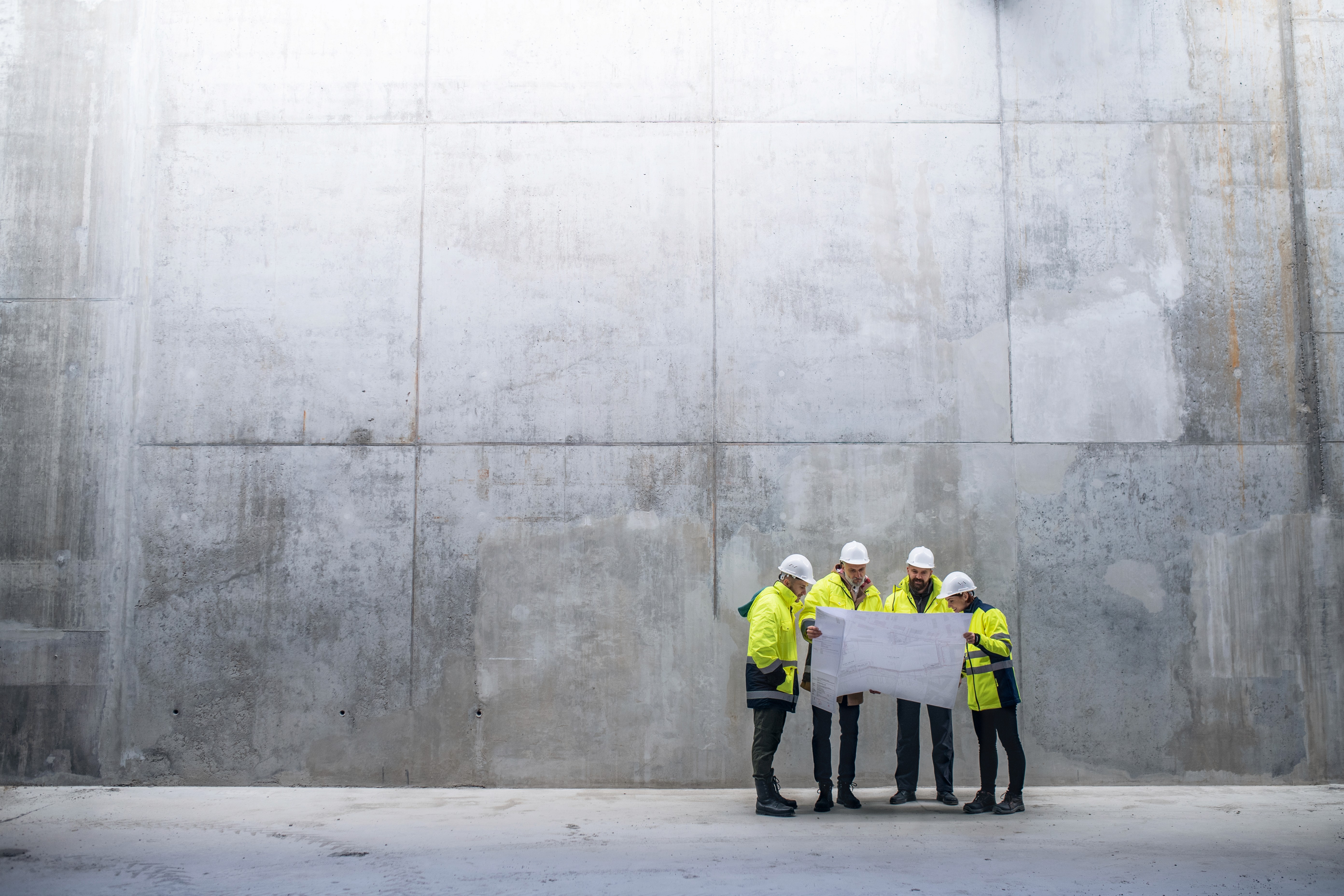 A group of engineers standing against a concrete wall.