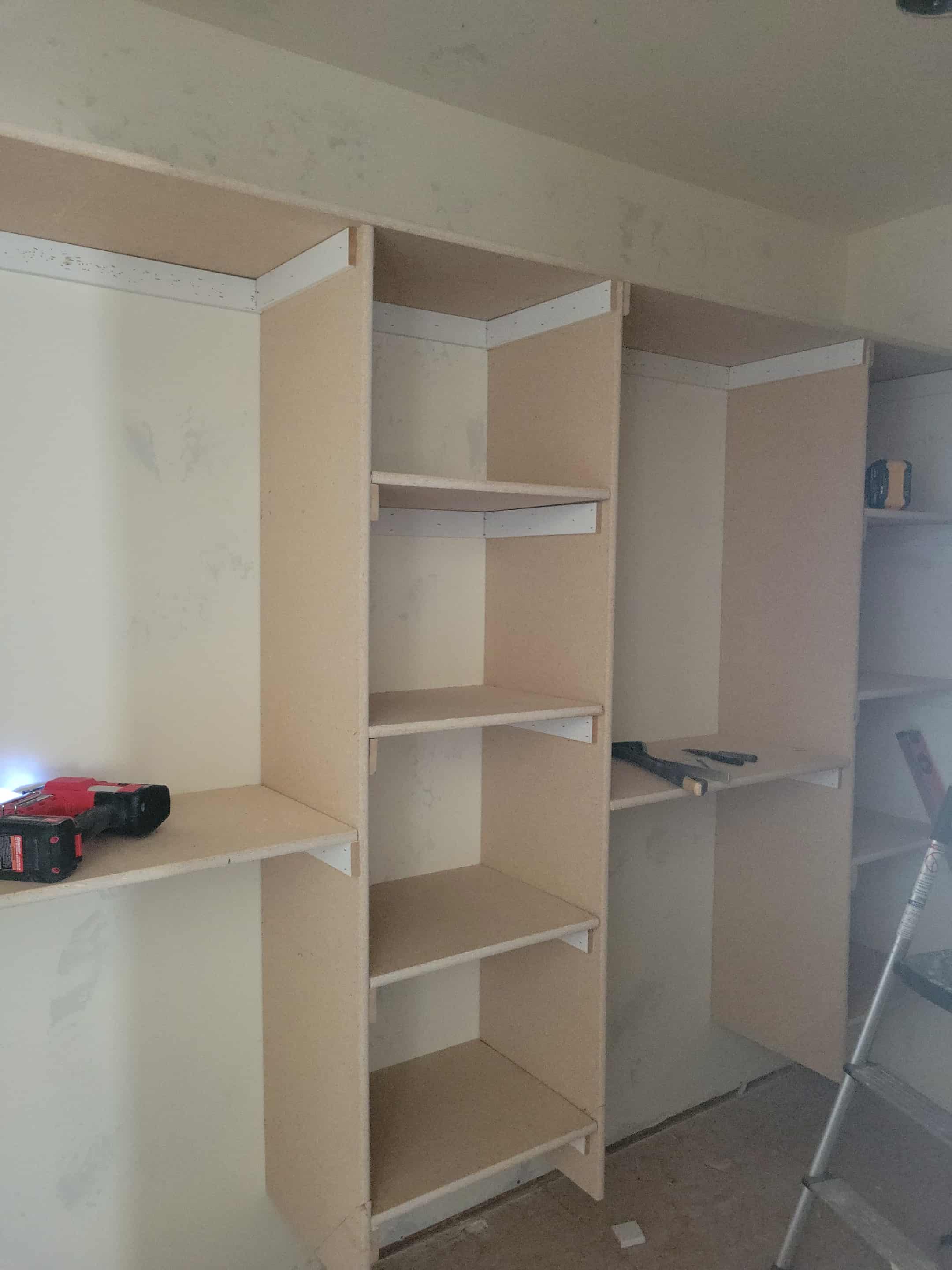A partially constructed shelving unit with open shelves, situated in an unfinished room.