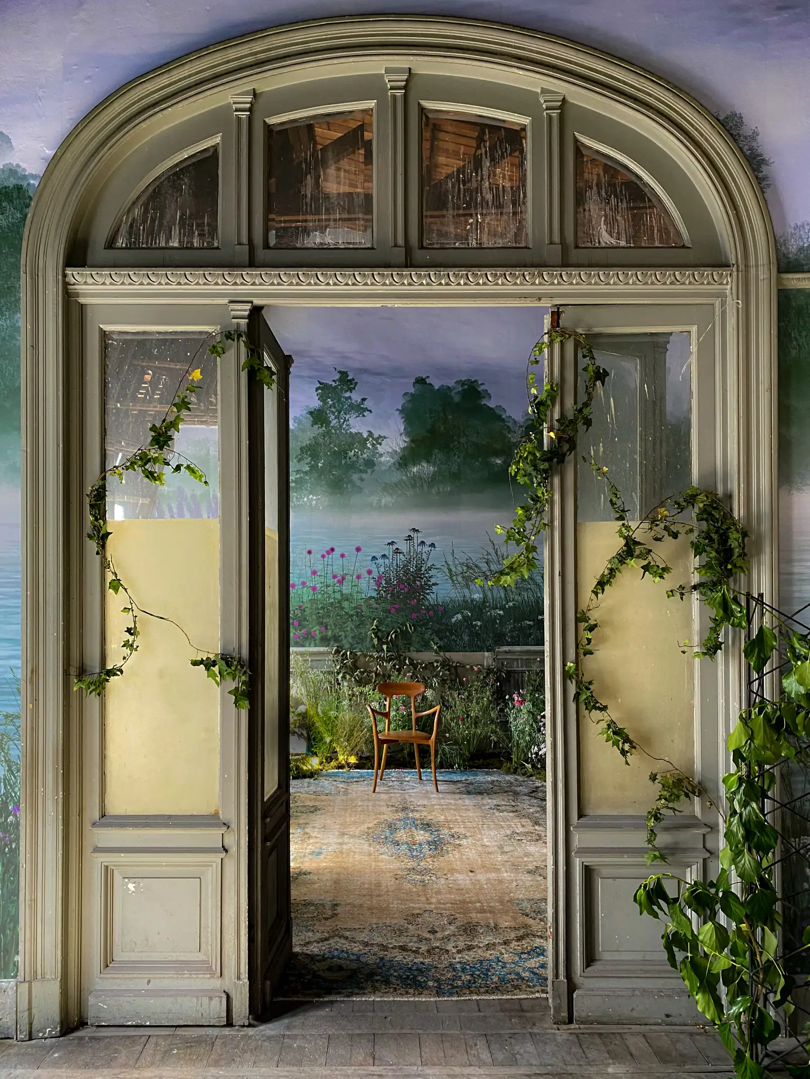 Puerta antigua abierta hacia jardín interior con plantas y luz natural para proyectos de diseño arquitectónico.