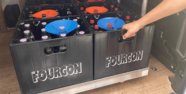 Casiers Le Fourgon remplis de bouteilles consignées, empilés à l'arrière d'une camionnette