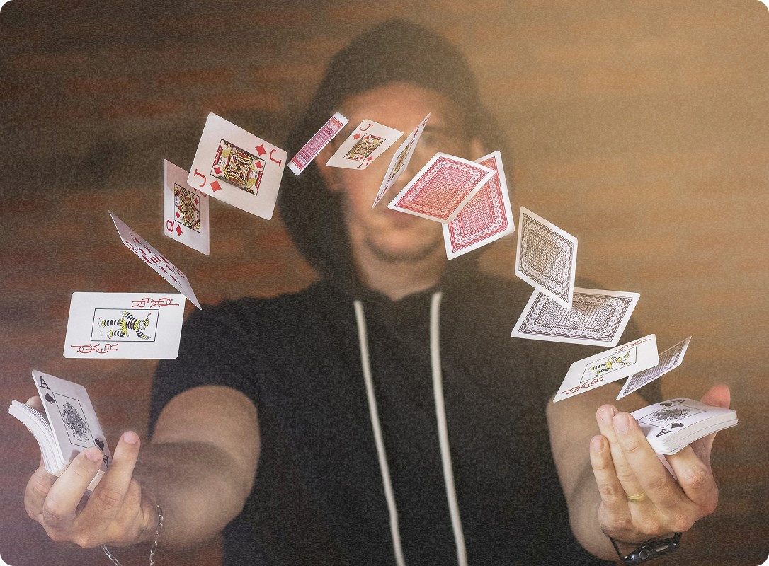 Un magicien lance des cartes dans l'air, les cartes flottant autour de ses mains tandis qu'il les manipule avec une grande précision