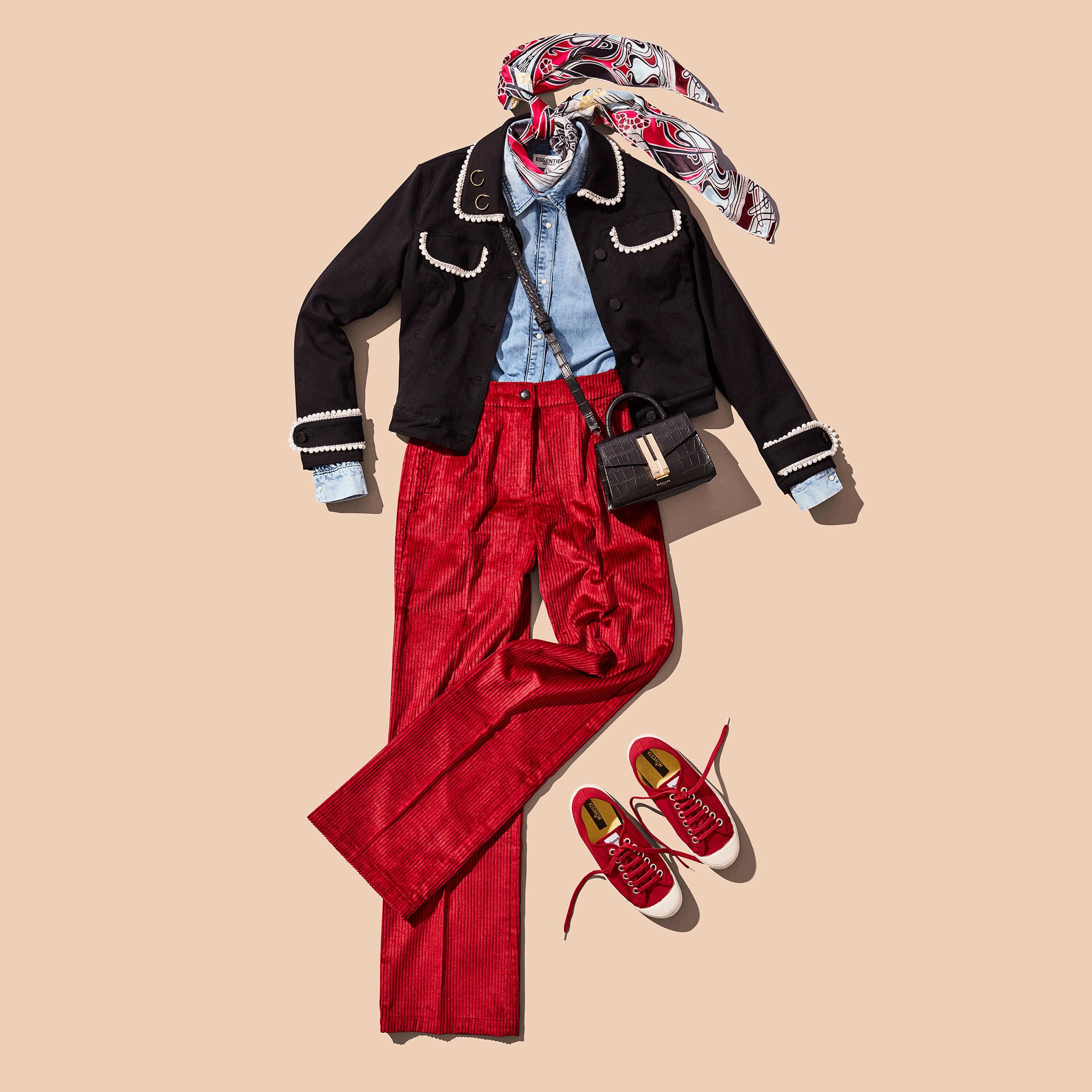 Fashionable outfit with black jacket, red trousers, denim shirt, patterned scarf, red sneakers, and a black handbag.