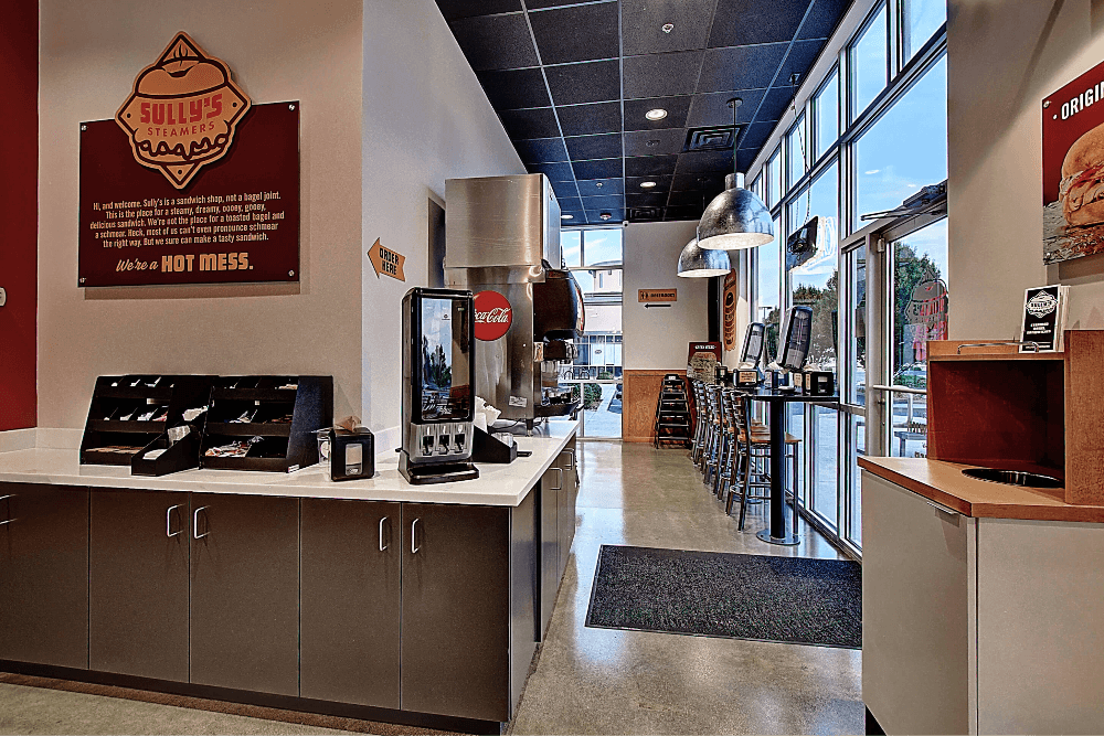Bright interior of a restaurant featuring a counter, menus, and a welcoming atmosphere.