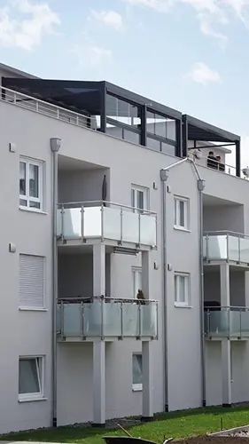 Mehrfamilienhaus mit verglaster Terrassenüberdachung auf der Dachterrasse