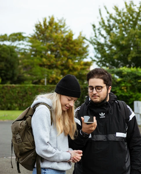 Two young people sharing content on a phone outside
