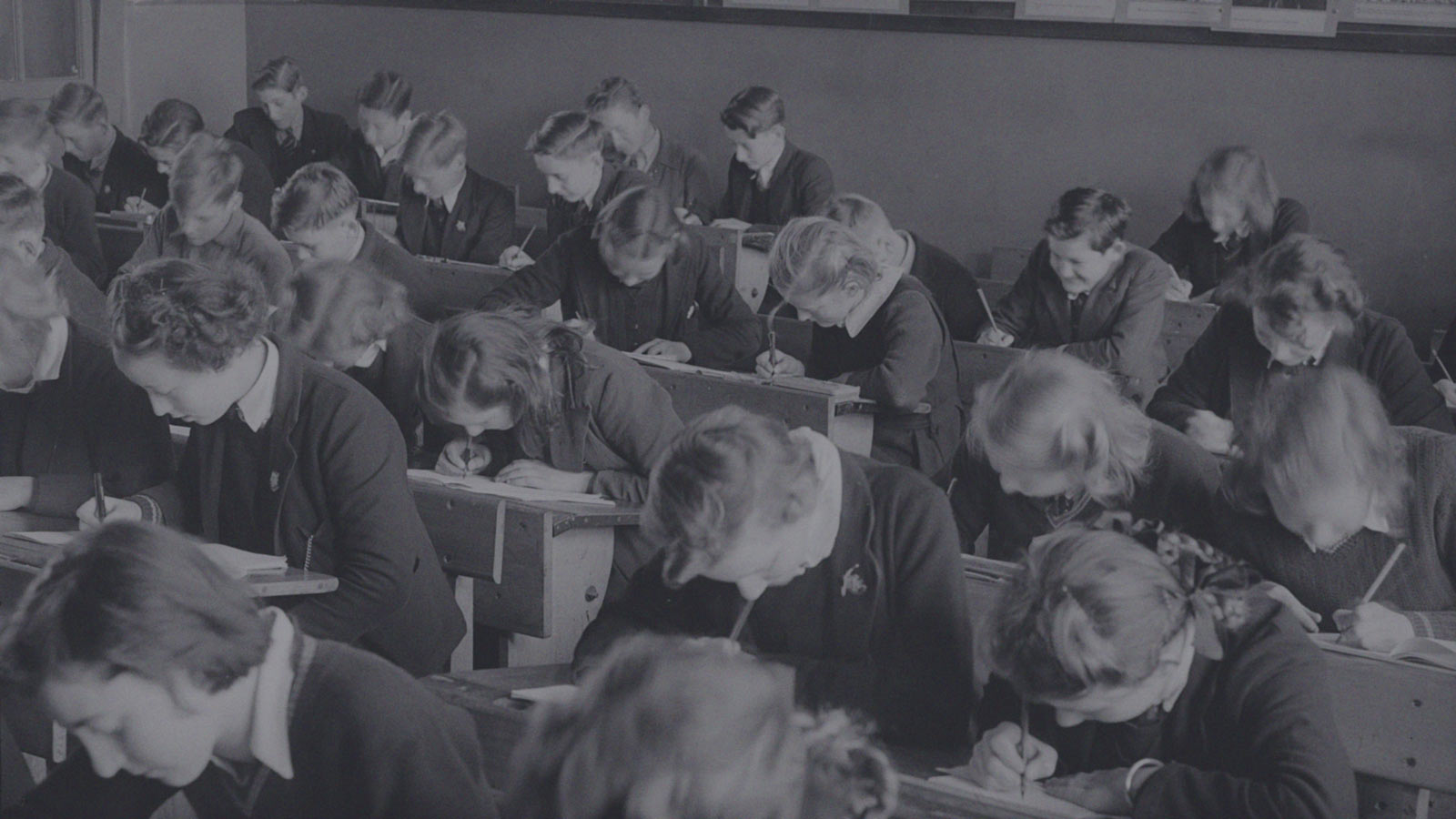Foto de alumnos en una sala de clases mientras anotan en sus cuadernos en la columna "Escuelas protegidas: un puntapié inicial" de IdeaPaís.
