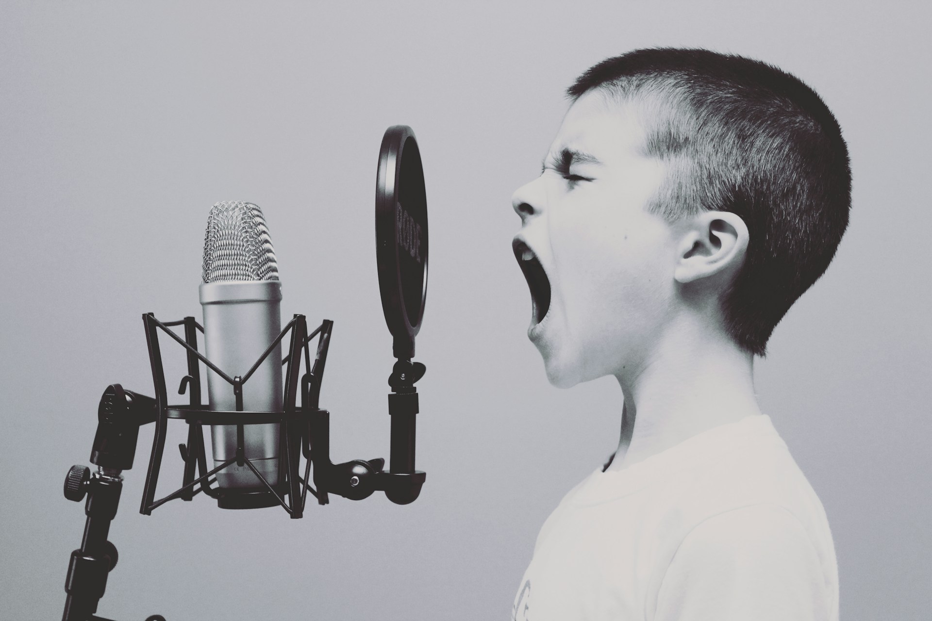 Young boy demonstrating his voice into a microphone