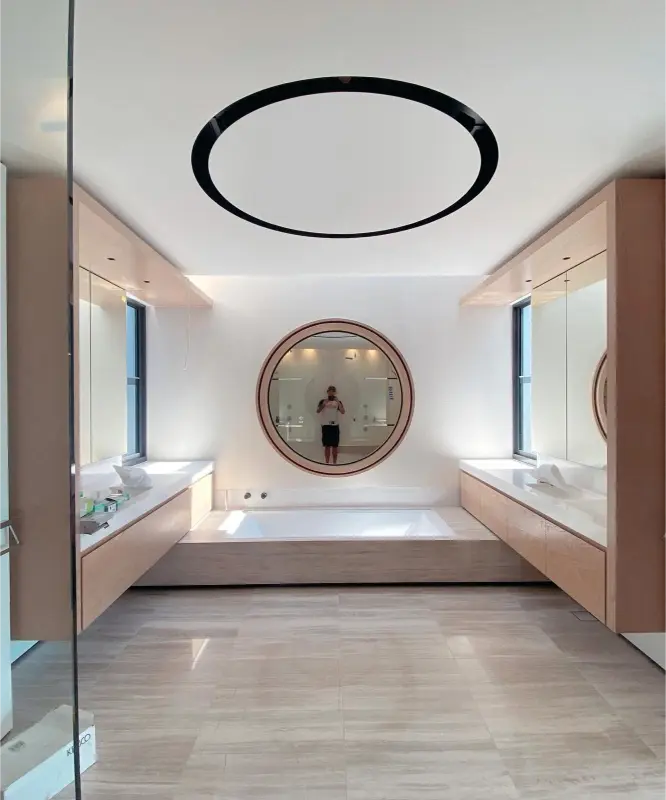 Bright modern bathroom with circular mirror and finished cabinetry