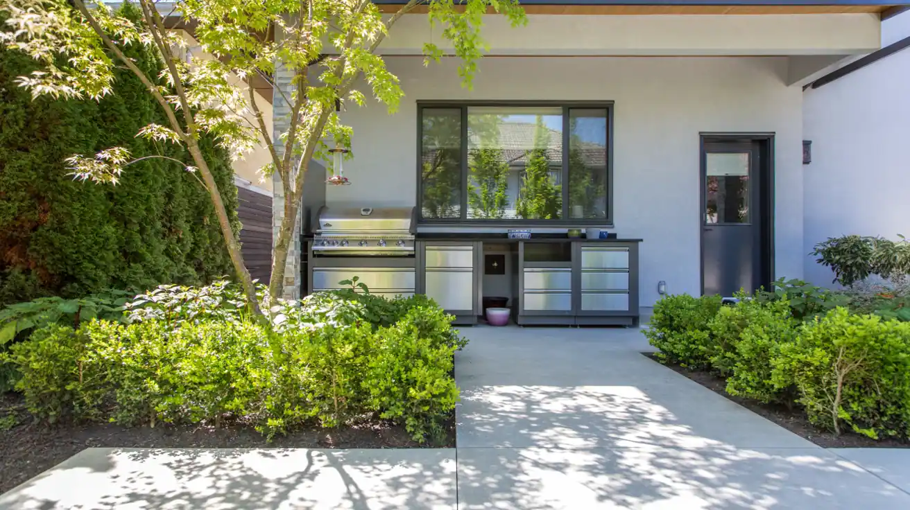 Outdoor kitchen and entertainment area with built-in BBQ, stainless steel appliances, concrete countertops, and covered patio space