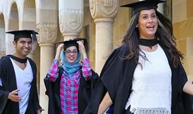 University of Queensland graduates outside a sandstone university building.