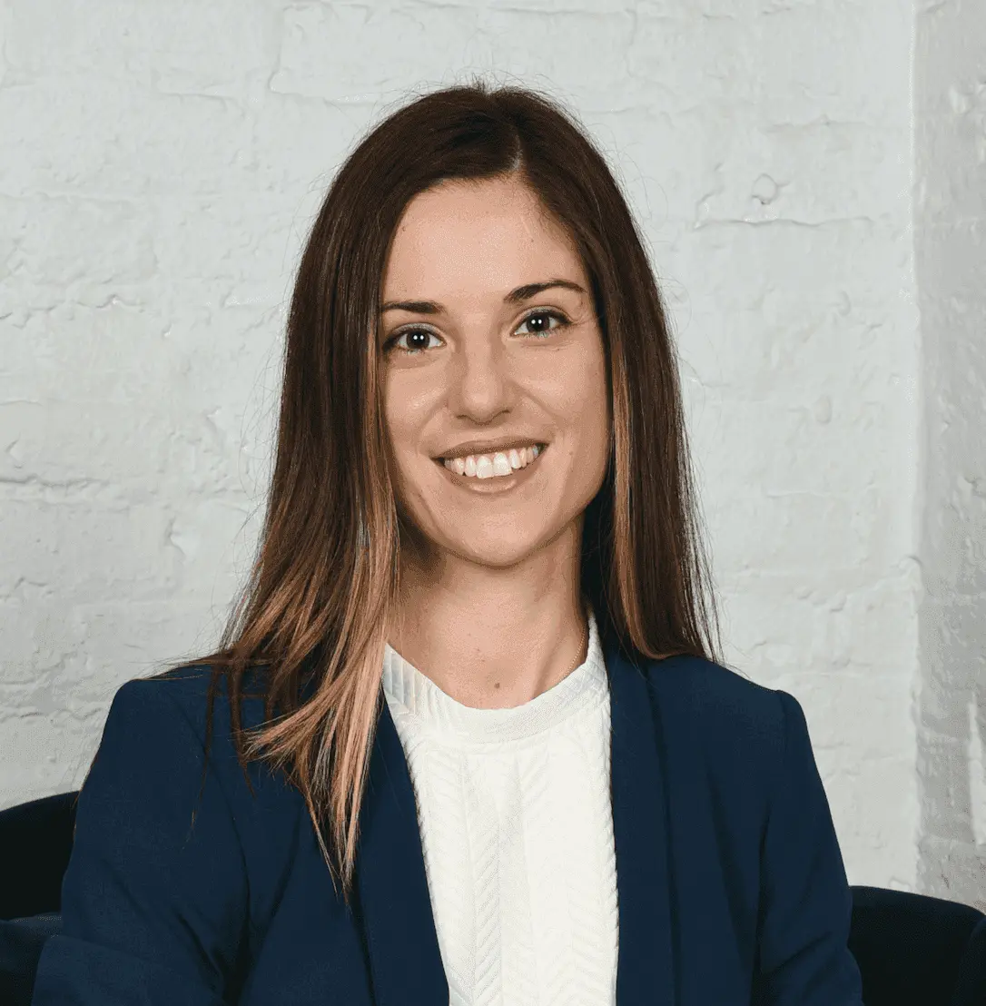 Woman in blue blazer and white top smiles.