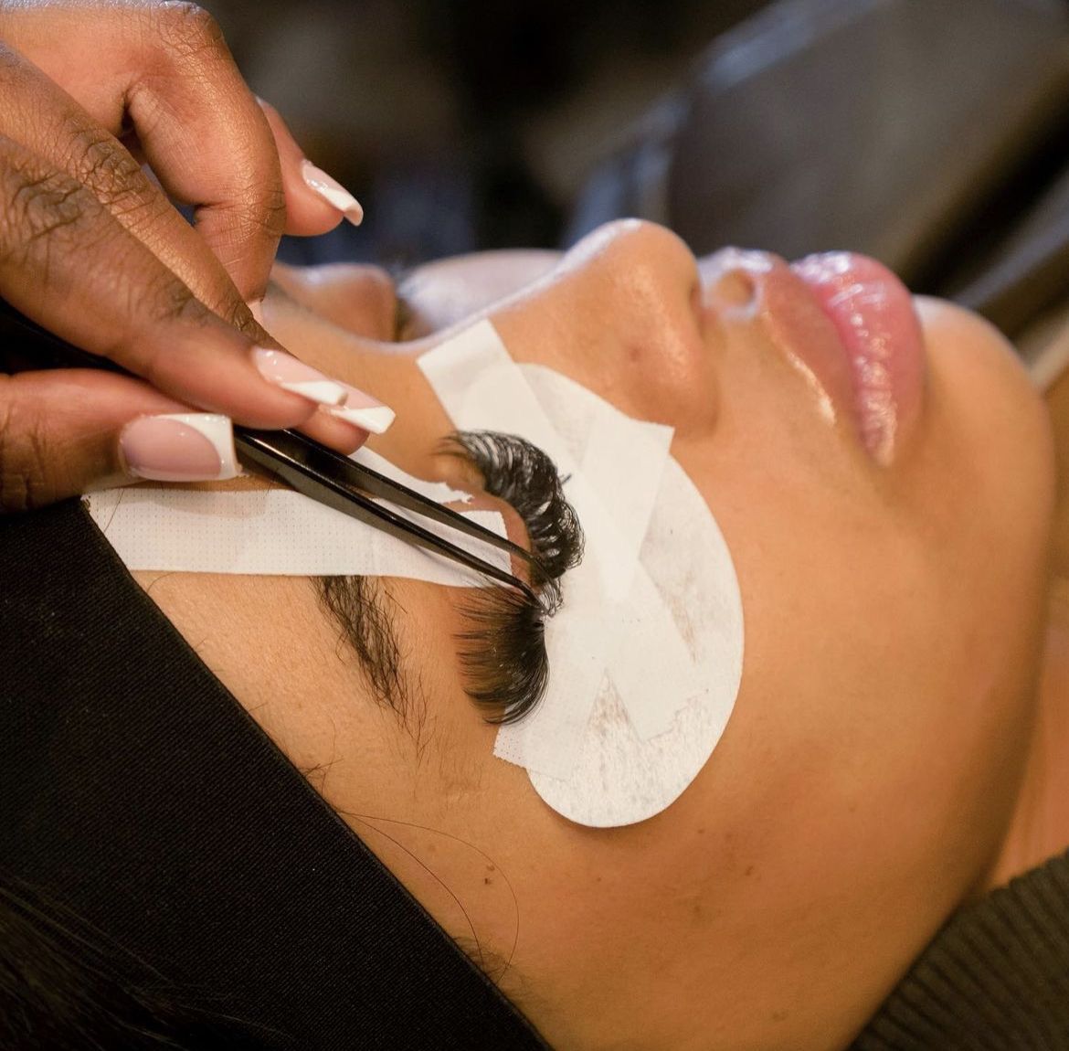 A group of colleagues sitting around a conference table with laptops, listening to a woman leading the meeting in a modern office setting.