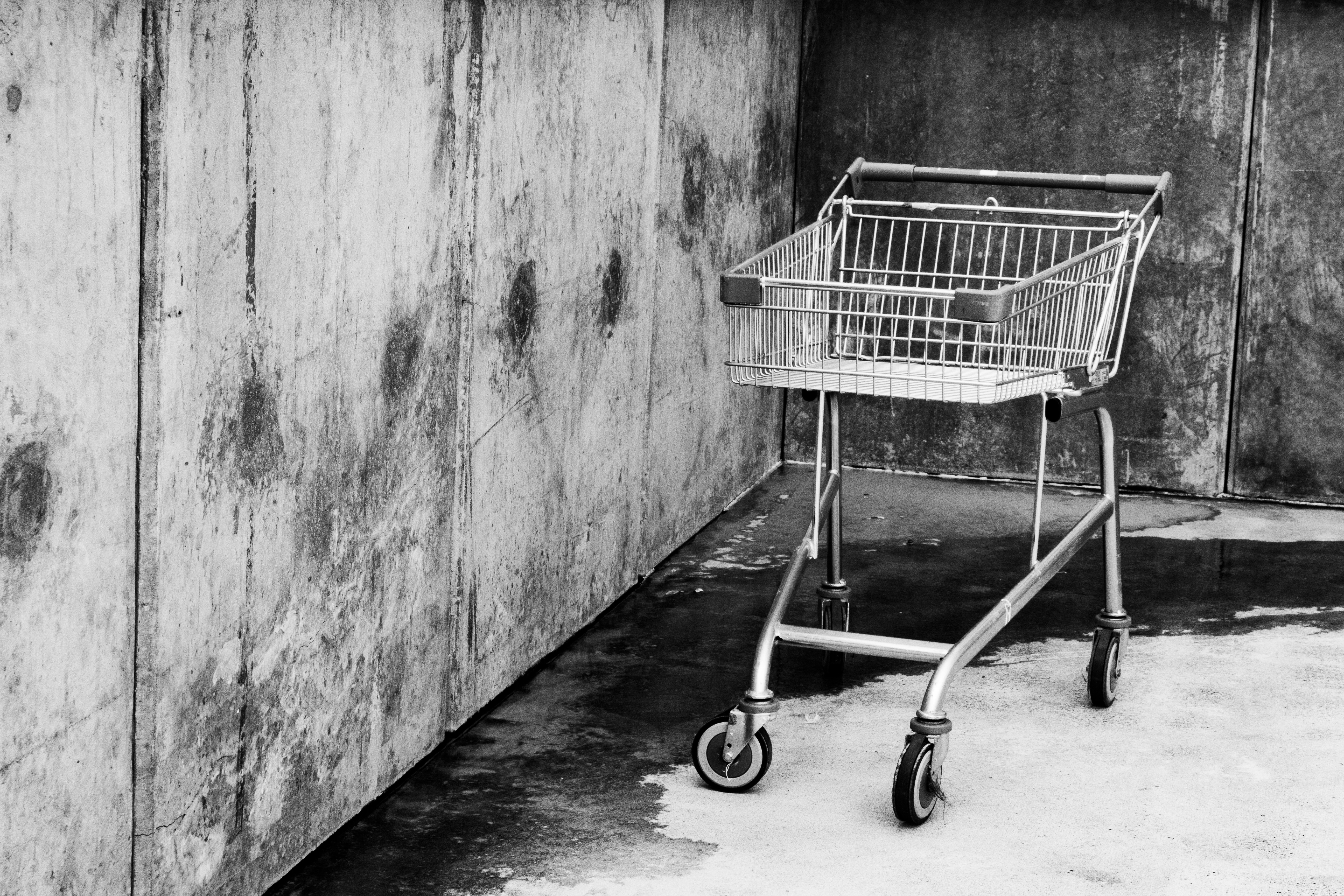 a shopping cart leaning against a concrete wall