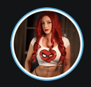 Stylish woman in a pink hat and tinted sunglasses posing outdoors against a bright blue sky, wearing colorful fashion layers in warm sunlight.