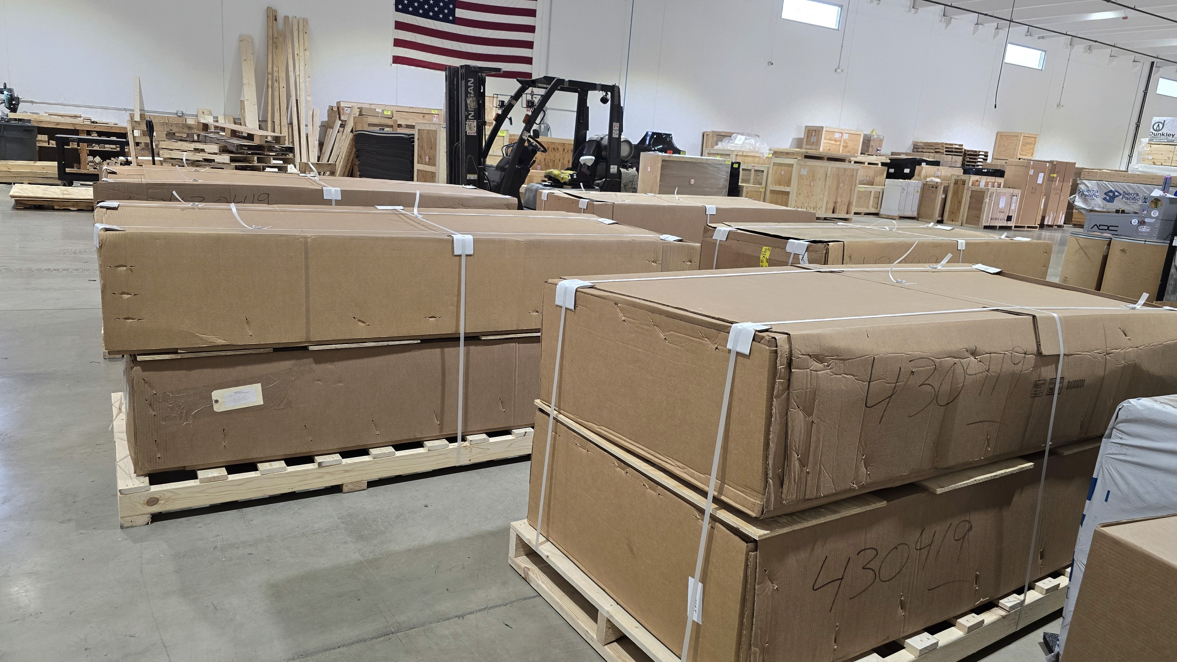 A smiling young man with crossed arms, wearing a plaid shirt and white t-shirt, poses against a dark background.