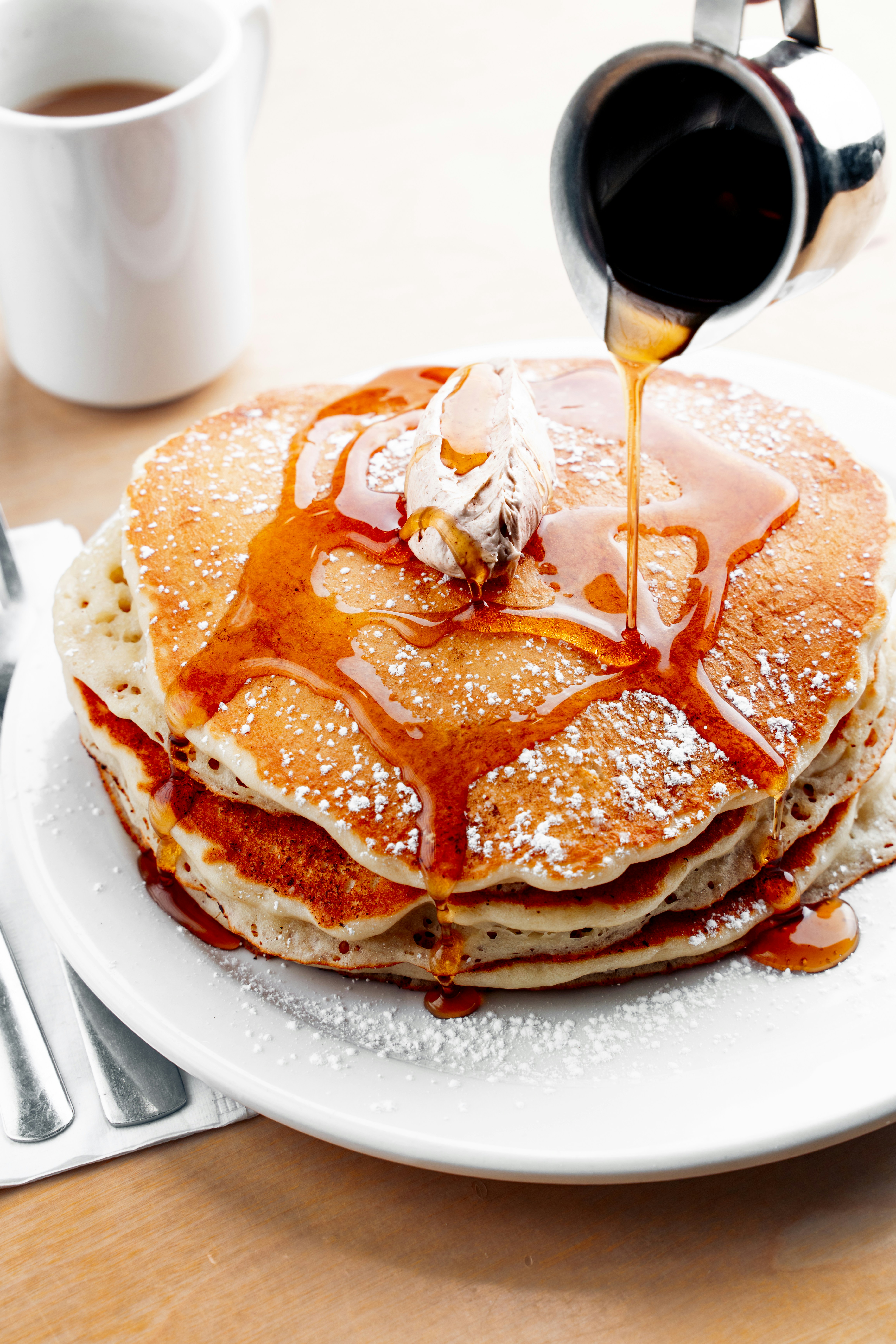 a stack of pancakes with syrup being drizzled on top