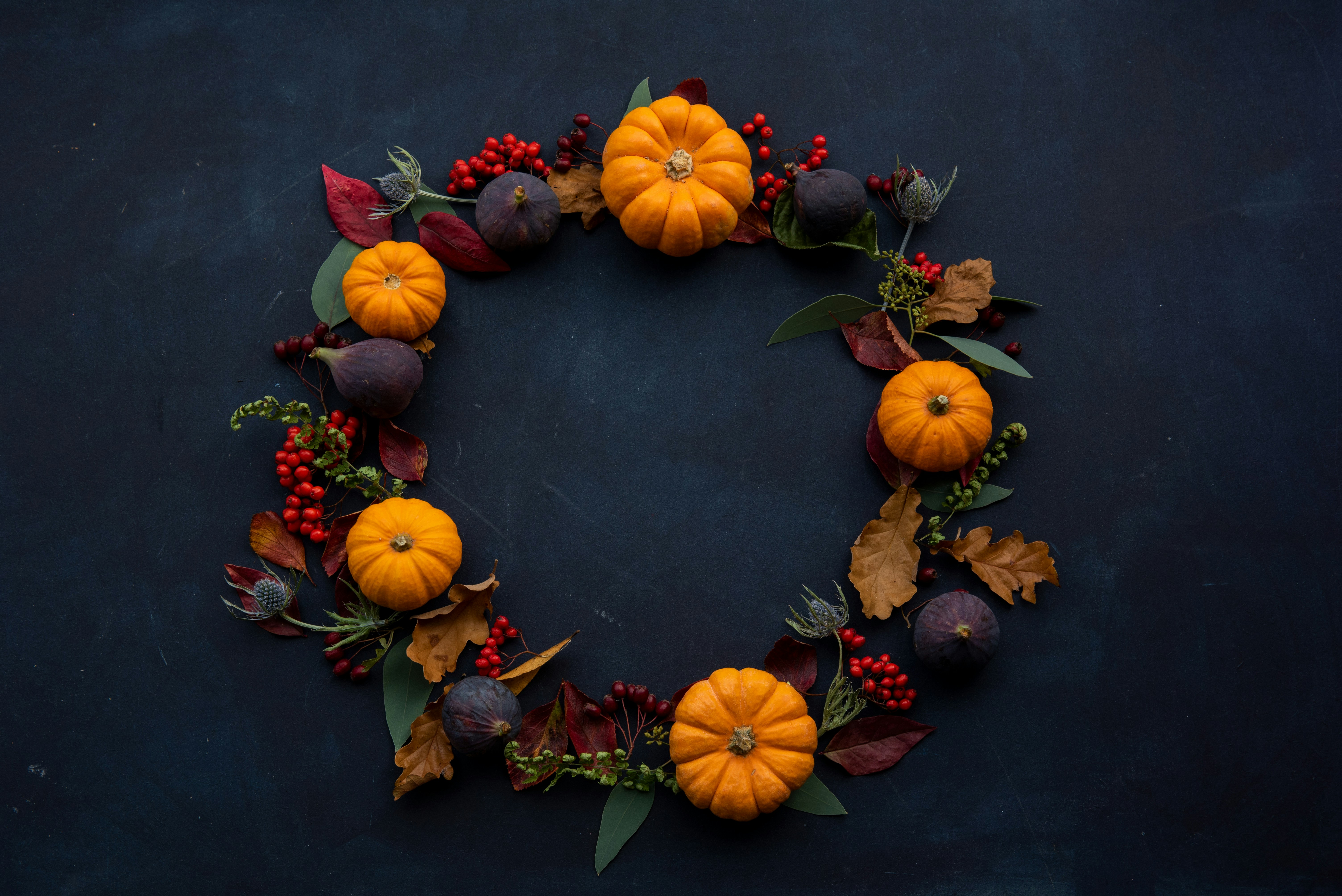 Elegant autumn wreath of mini pumpkins, berries, and leaves on a dark moody background