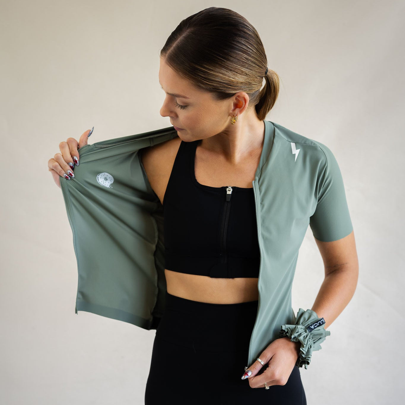 Cyclist lifting LUCA Soleil jersey in matcha to show interior fit and hidden donut print