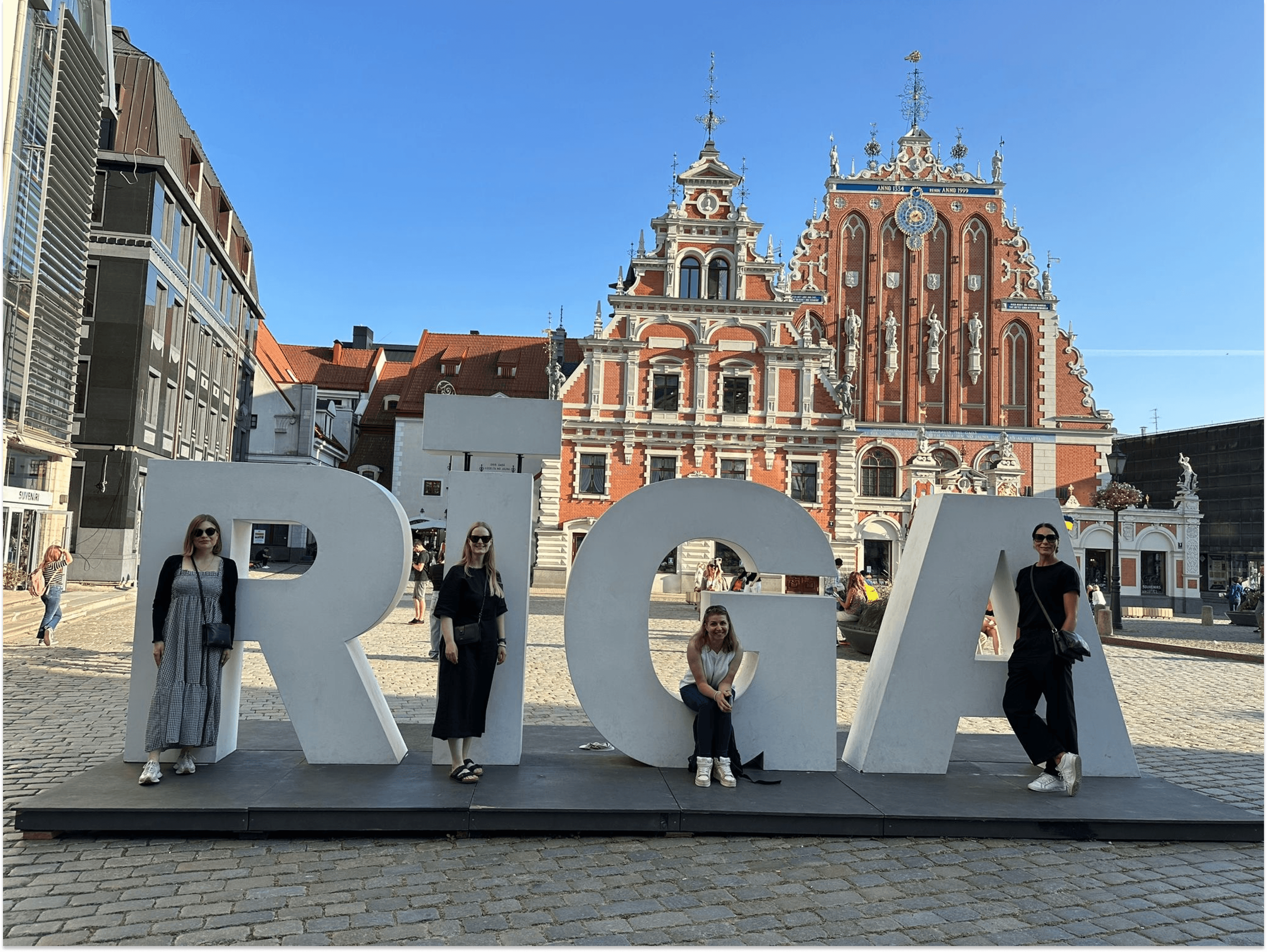RIGA city sign and four people stood in front of it