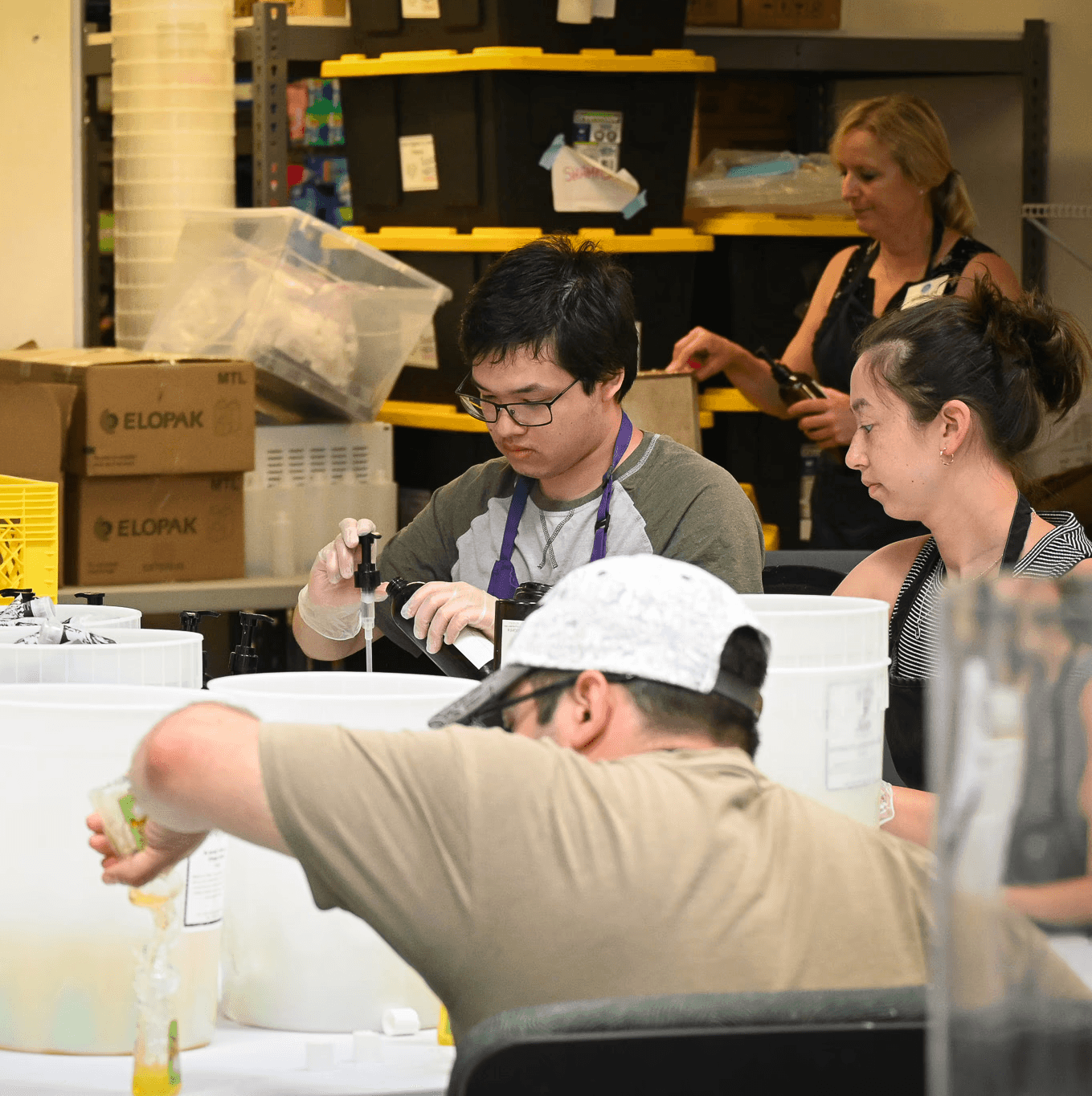 Volunteers working in warehouse, the are filling shampoo bottles