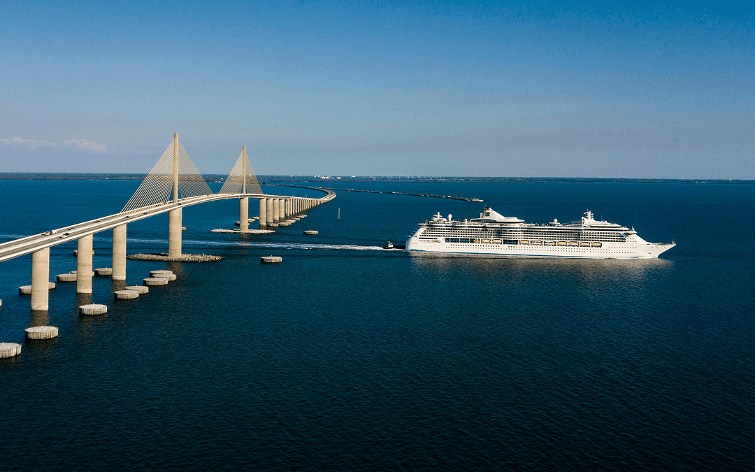 Large cruise ship navigating clear blue waters near a concrete causeway bridge, representing maritime commerce in the Terra Ceia Aquatic Preserve area