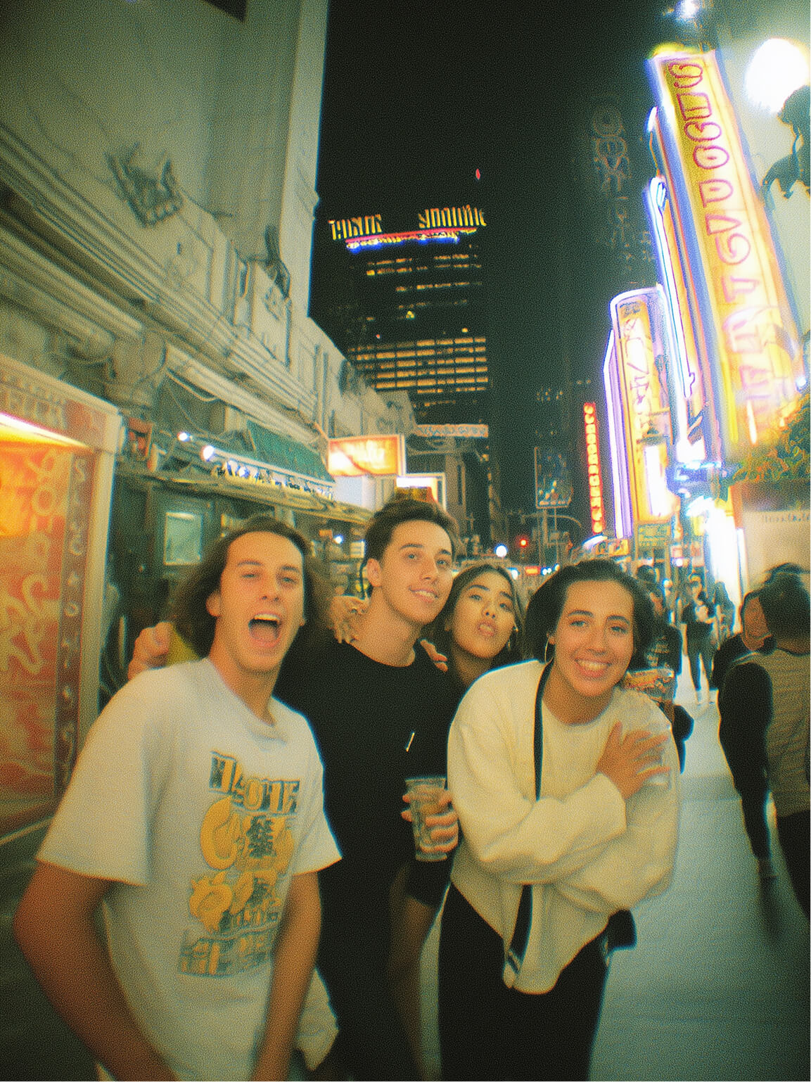 Group of friends smiling on a lively city street at night