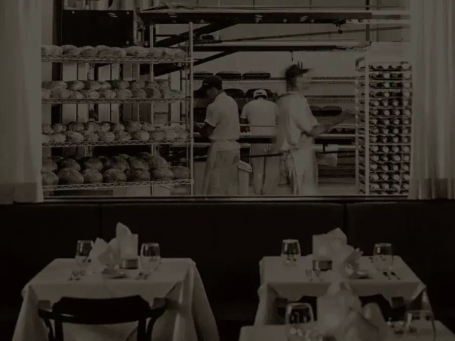 Restaurant dining room interior showing the bakery window with bakers freshly baking bread in the ovens