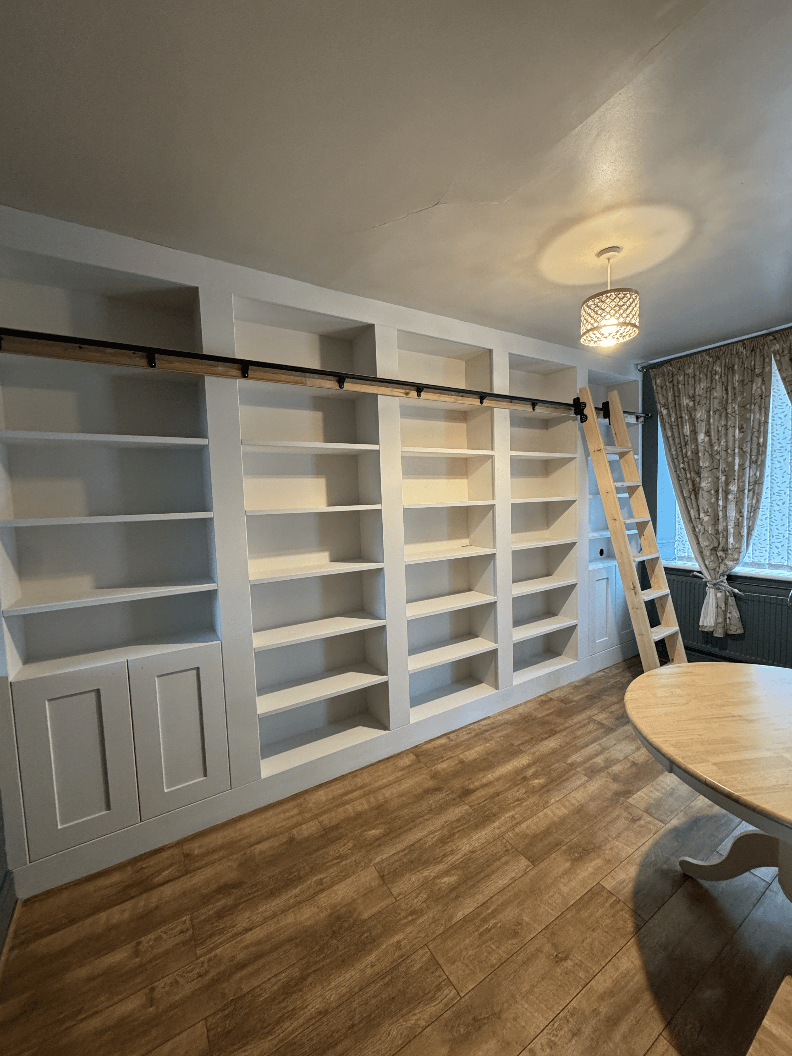 A modern hallway features vibrant teal and orange geometric and leaf patterns, with glossy tiled floors, a large rectangular light fixture, and a small shelf holding a potted plant, all leading to a large, frosted window at the end.