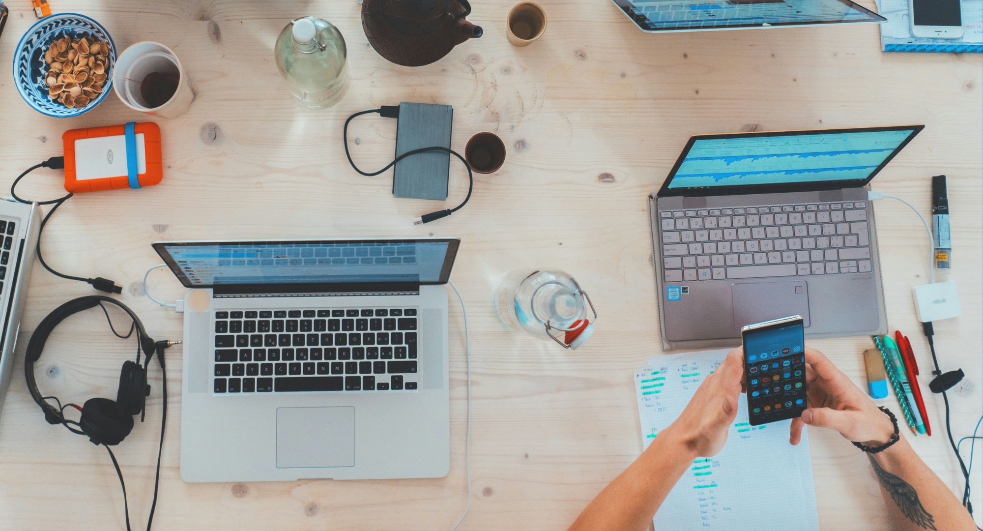 mesa de escritório vista de cima com notebooks e outros materiais de trabalho