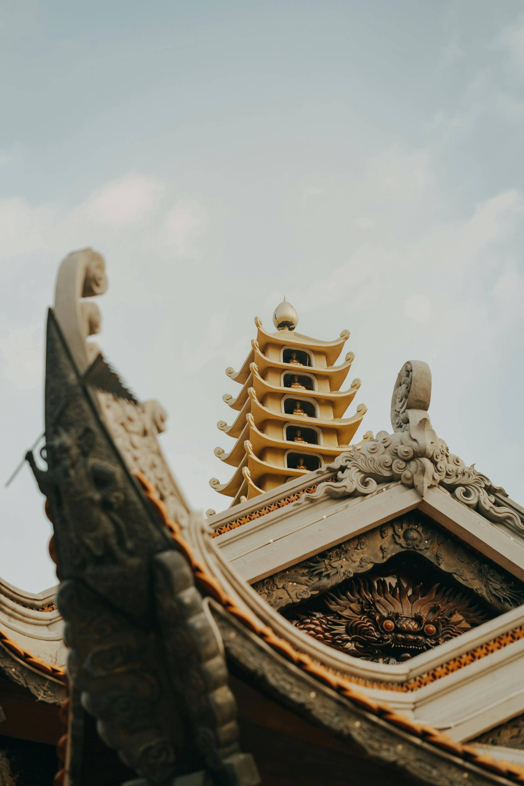 Intricate carvings and elegant roof design of a Vietnamese temple against a clear sky.