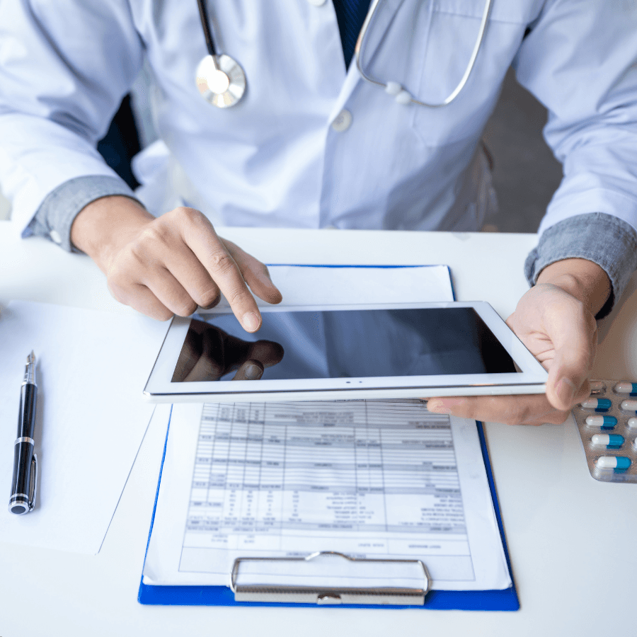 Medical transcription software aiding a physician as they update a digital chart with a tablet at a desk