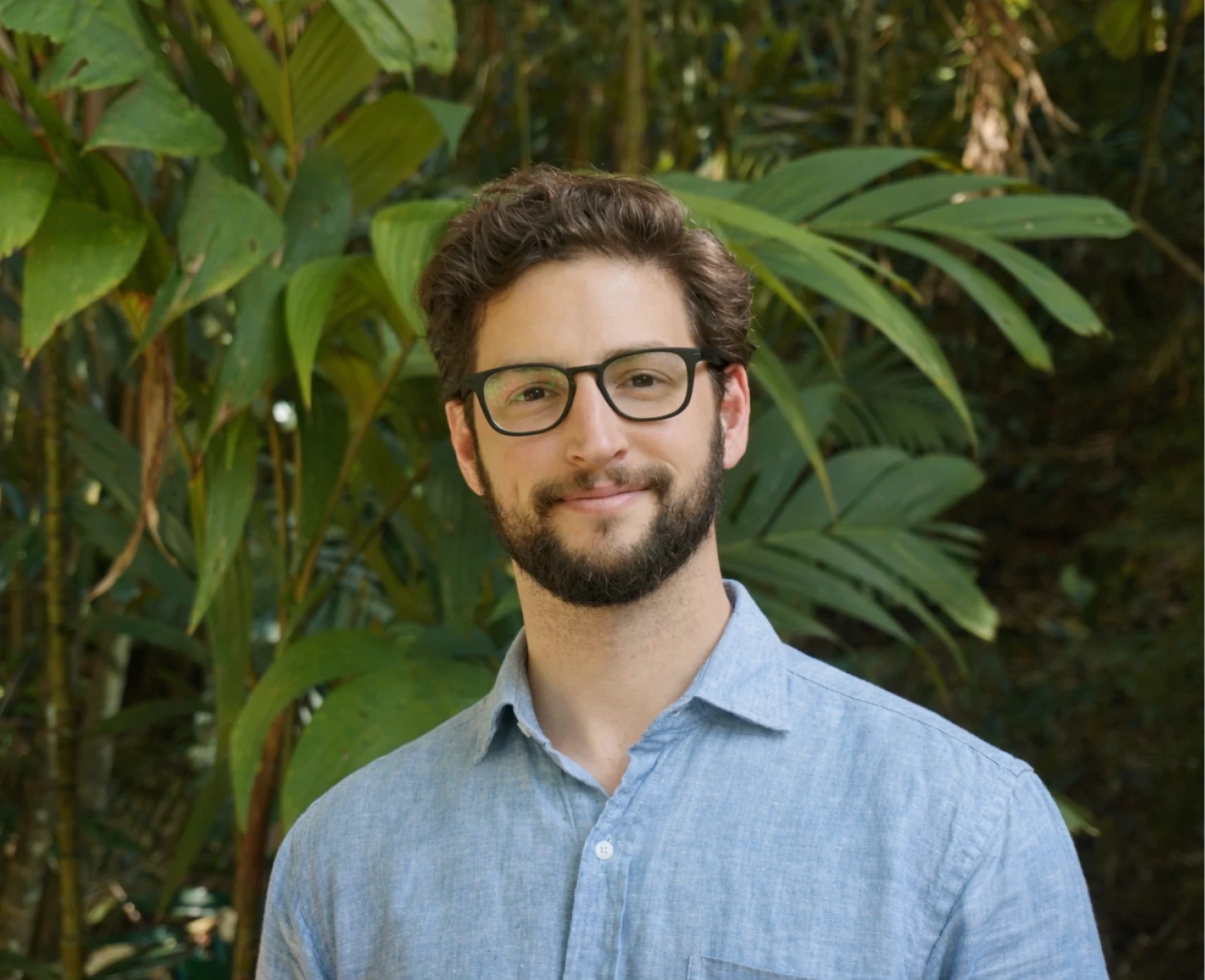 Man smiling and standing next to a redwood tree