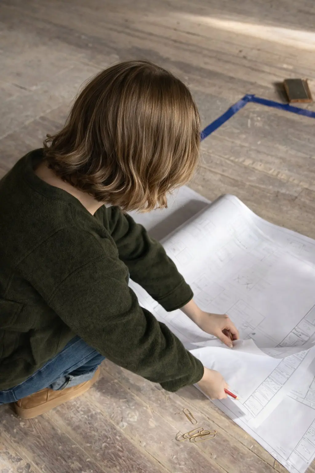 Architecte d'intérieur vérifiant des plans au sol pendant le suivi de chantier d'un local professionnel