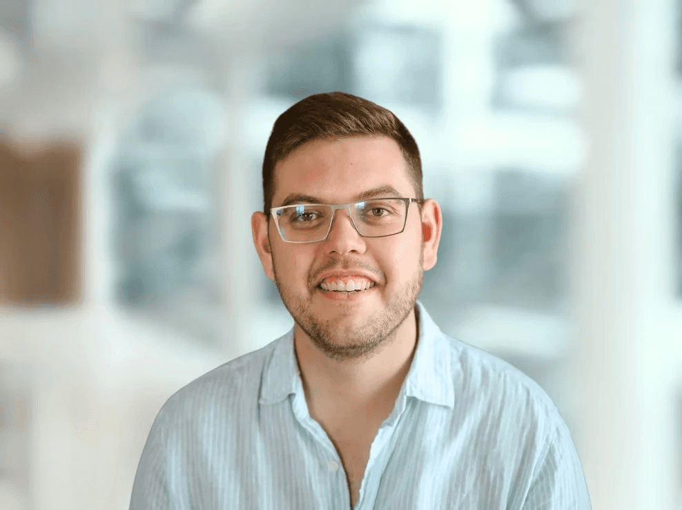 Porträt eines lächelnden Mannes mit Brille vor hellem Hintergrund im Büro