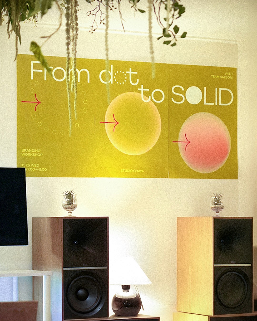 White plate with roasted carrots served on green sauce, topped with almonds and fresh herbs, held by a hand over a dark table.