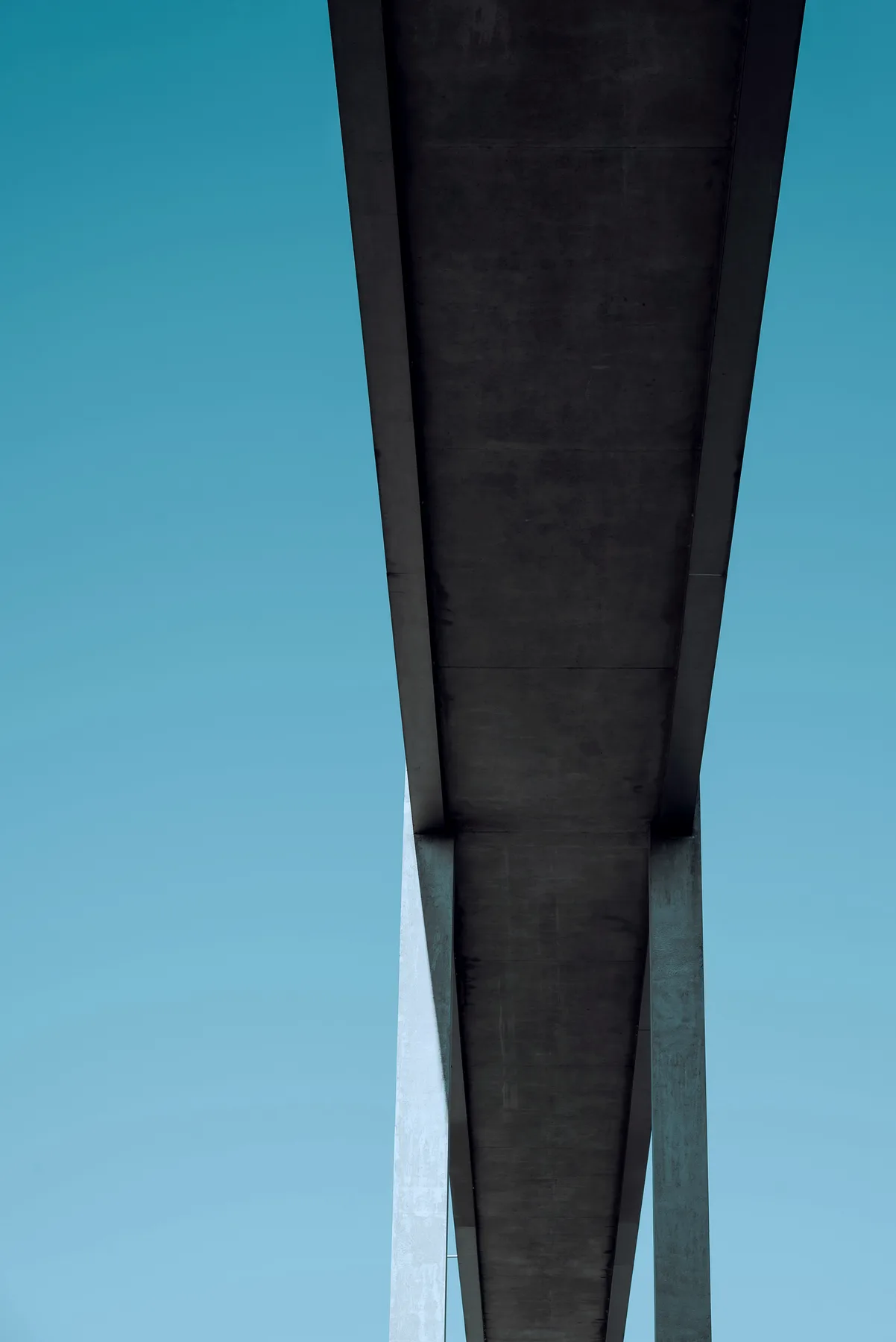Underside of a concrete bridge against teal sky