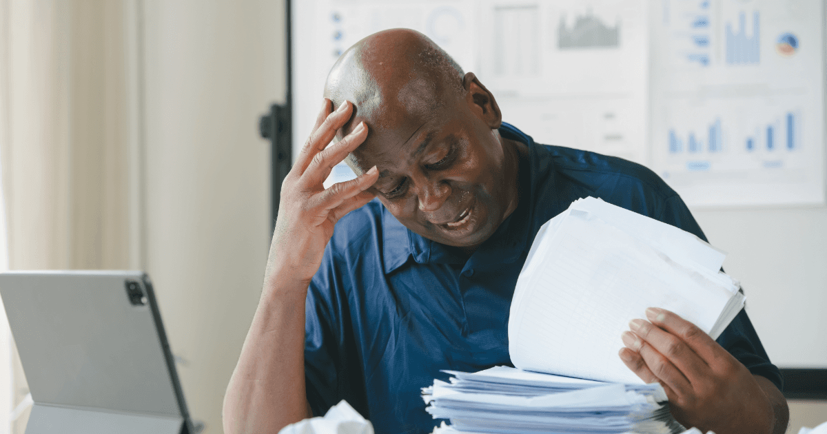 Frustrated office worker surrounded by paperwork, showing the inefficiency of manual order-to-cash processes.