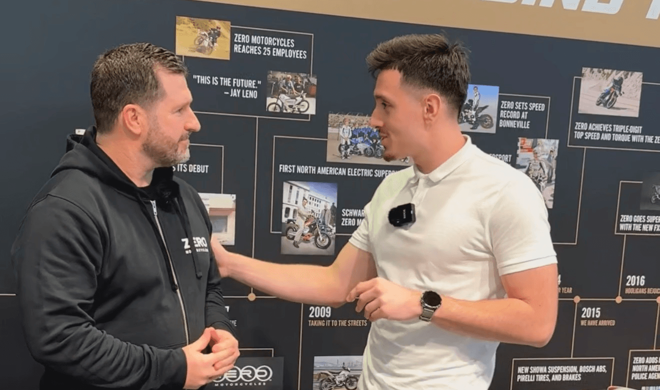 Marin interviewing a founder at an industry event in front of a Zero Motorcycles company history wall.