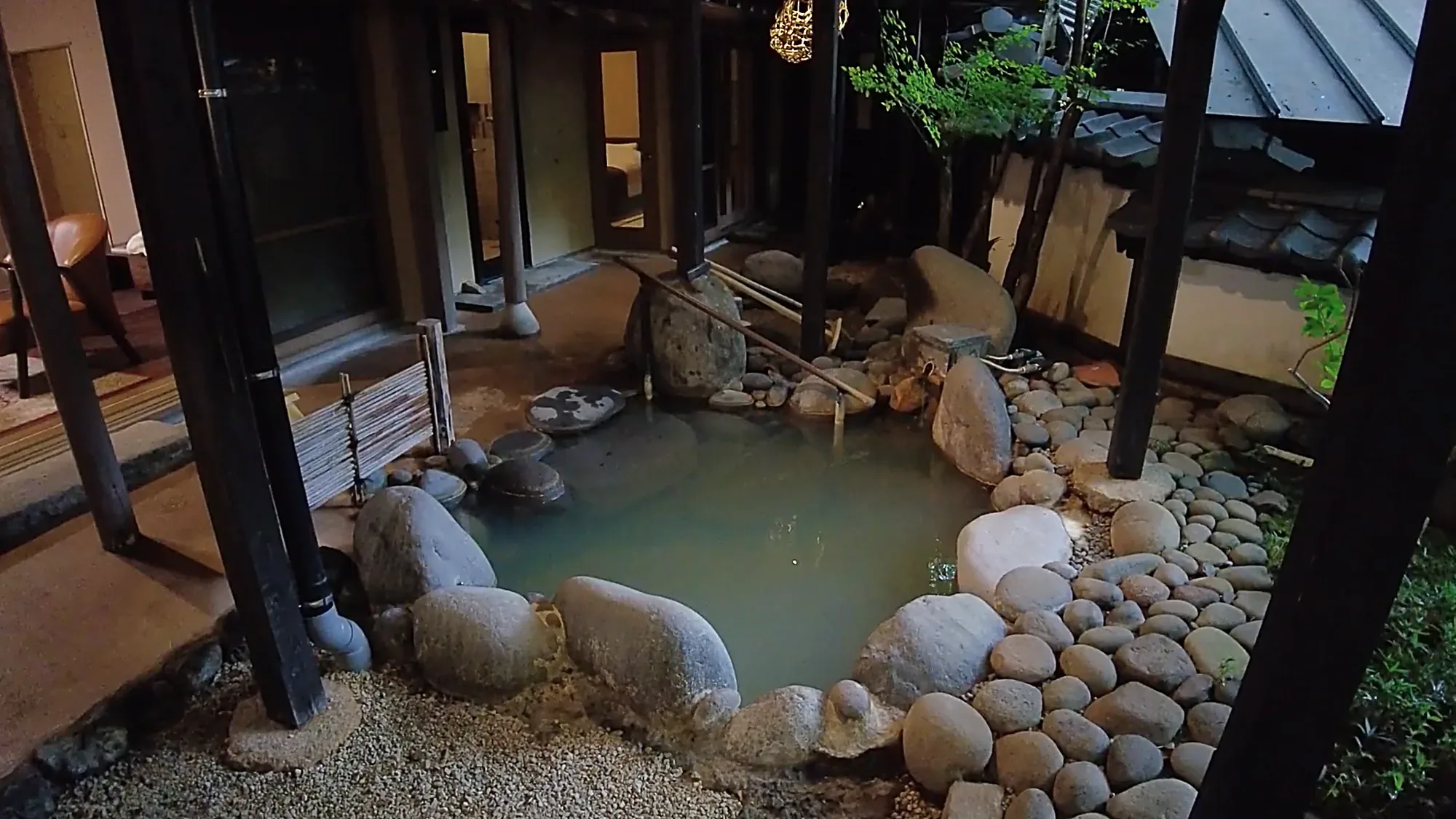 A stone-lined bathing pool inside a timber courtyard at Kurokawa Onsen