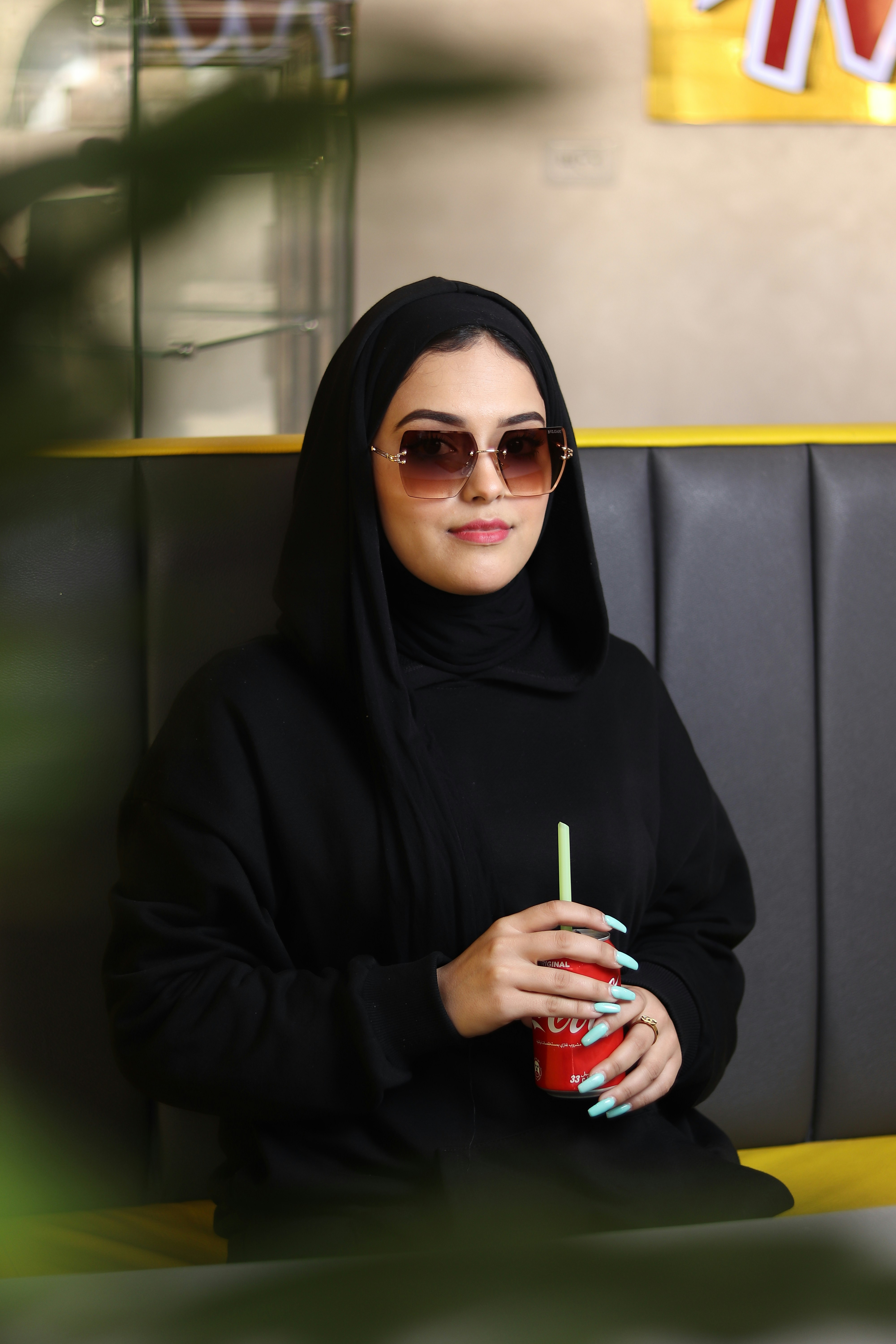 a woman wearing a black head scarf and holding a drink